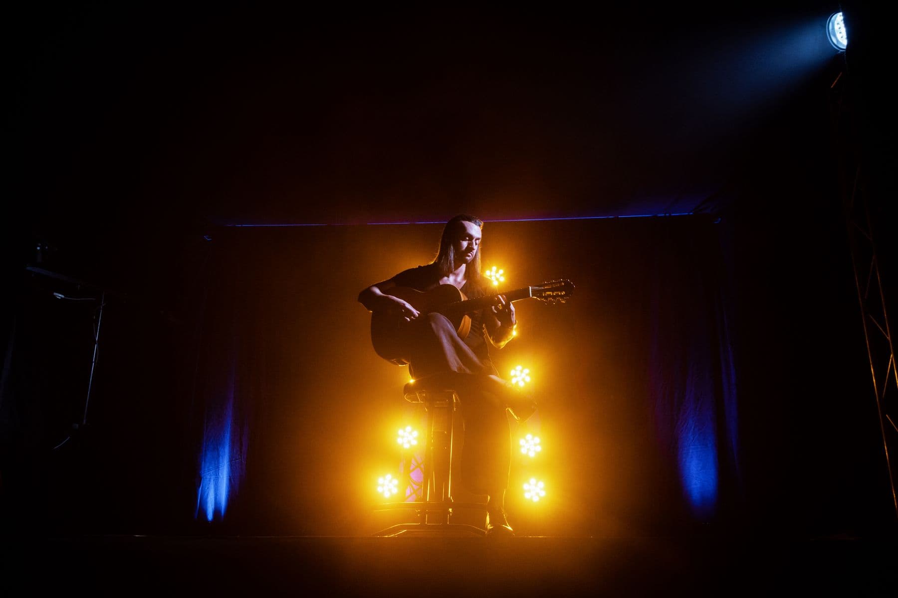 Scenă cu lumini calde și un chitarist în concert